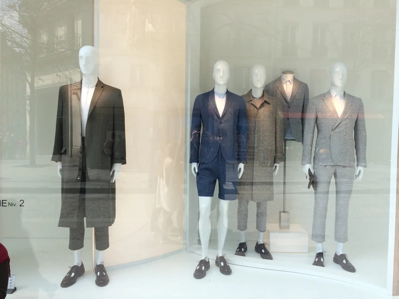 Escaparate masculino con cinco maniquíes de sastrería visto desde la calle