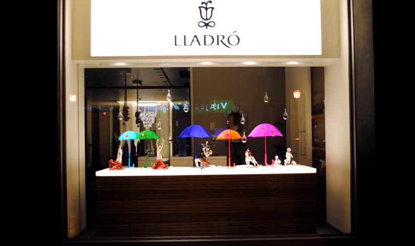 Escaparate de Lladró con sombrillas de colores sobre figuras blancas
